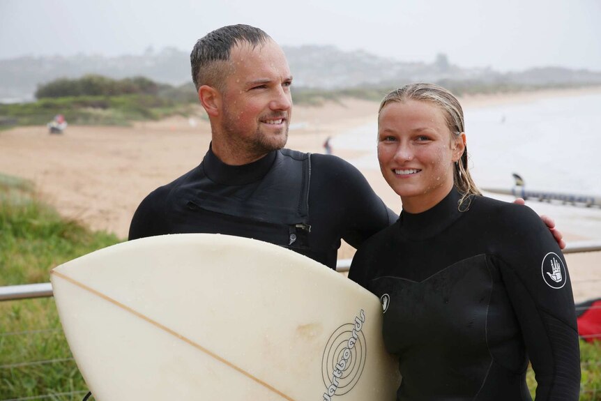 a man and woman with surfboards in the rain
