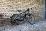 A black electric bicycle in front of a wall.