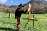 Warwick Fuller paints with mountains in the background.