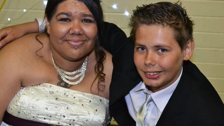 A woman in her wedding dress with a young boy in a suit.