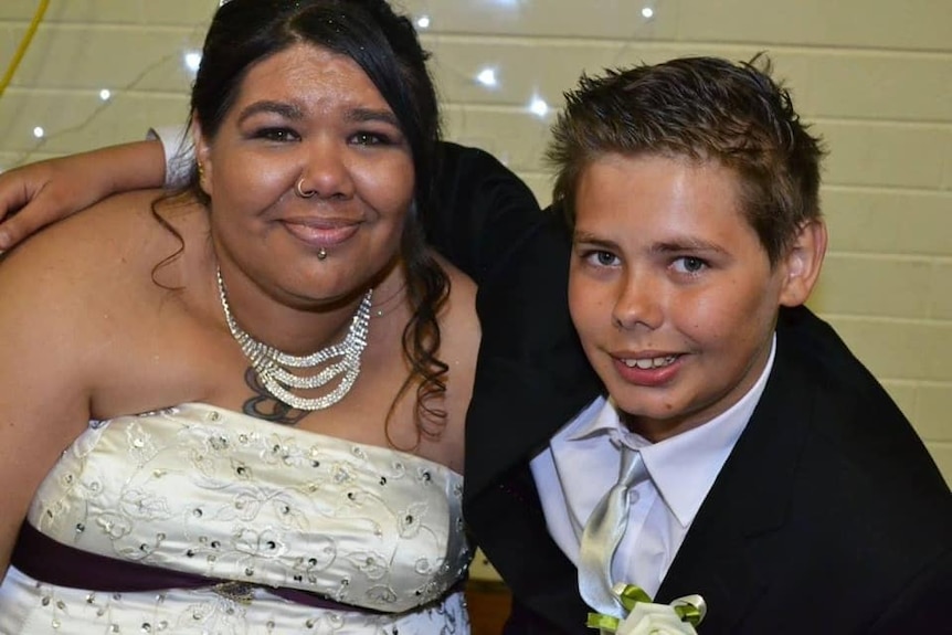 A woman in her wedding dress with a young boy in a suit.