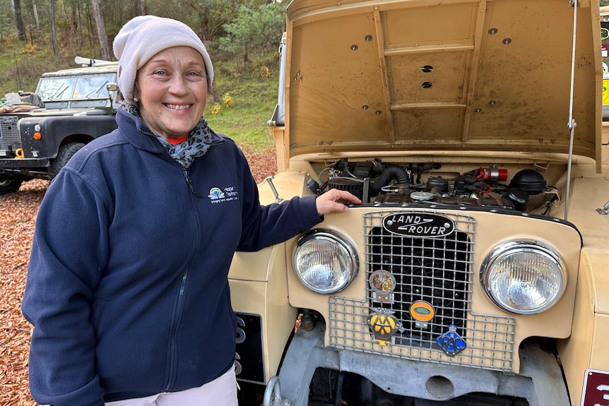 A woman stands next to a land rover