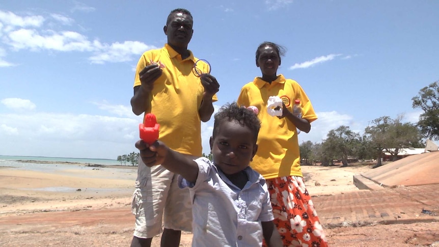 Three people on a beach with toys