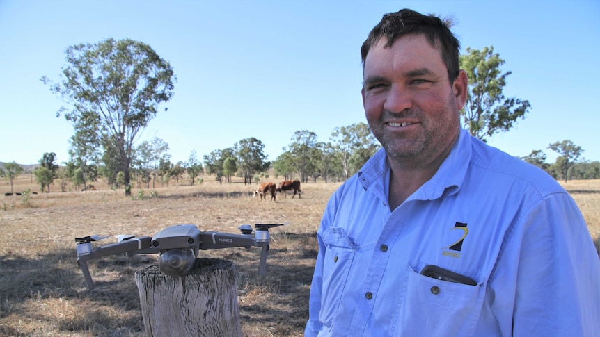 Will Wilson stands in a paddock with his drone on a stump