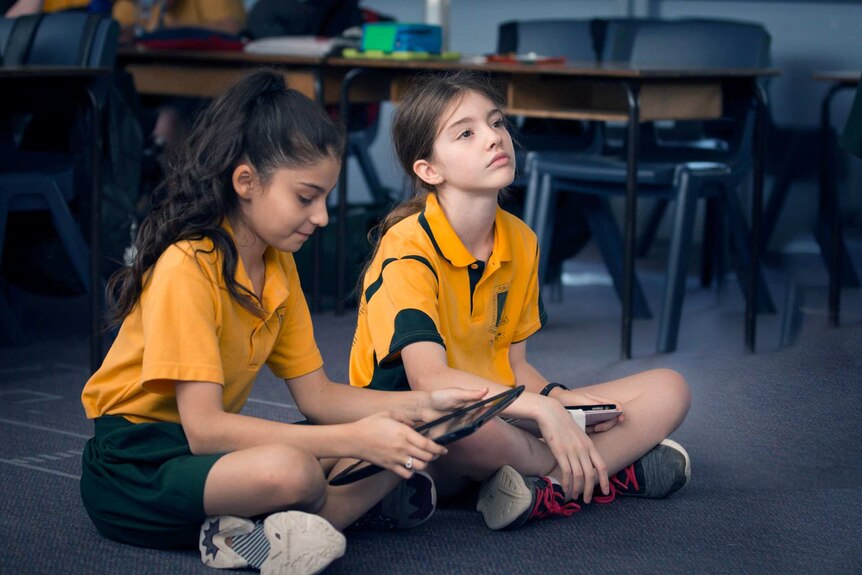 Photo of two primary school students sitting on the classroom floor