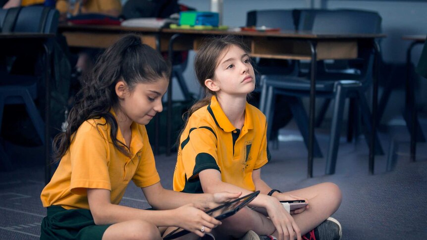 Photo of two primary school students sitting on the classroom floor