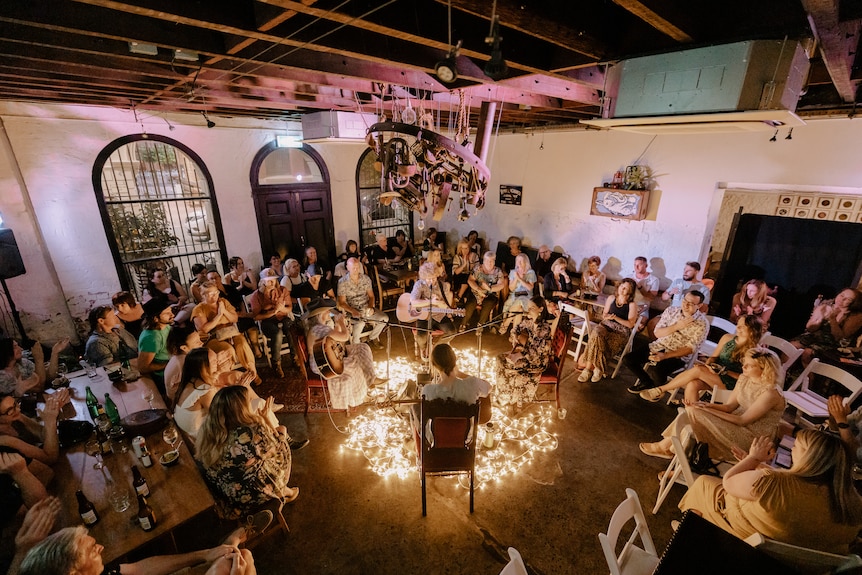 a room-full of people sitting around four musicians