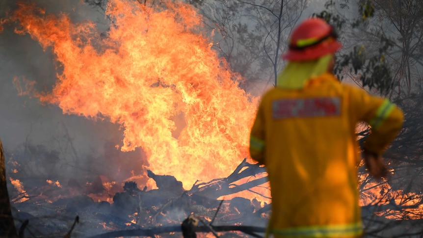 A firefighter in uniform stands in front of a fire in Torrington