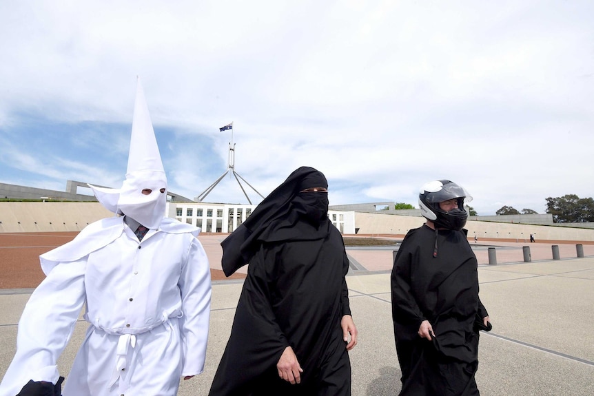 Men wearing a Ku Klux Klan outfit, a motorbike helmet and a niqab leave Parliament House.