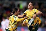 Two members of the Matildas leap in the air with joy to celebrate a goal.