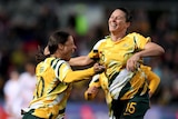 Two members of the Matildas leap in the air with joy to celebrate a goal.