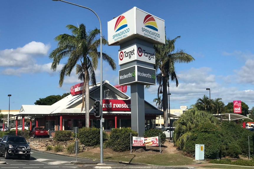 Palms trees and signage at the corner of the Springwood Shopping Centre, with Red Rooster fast food outlet in background