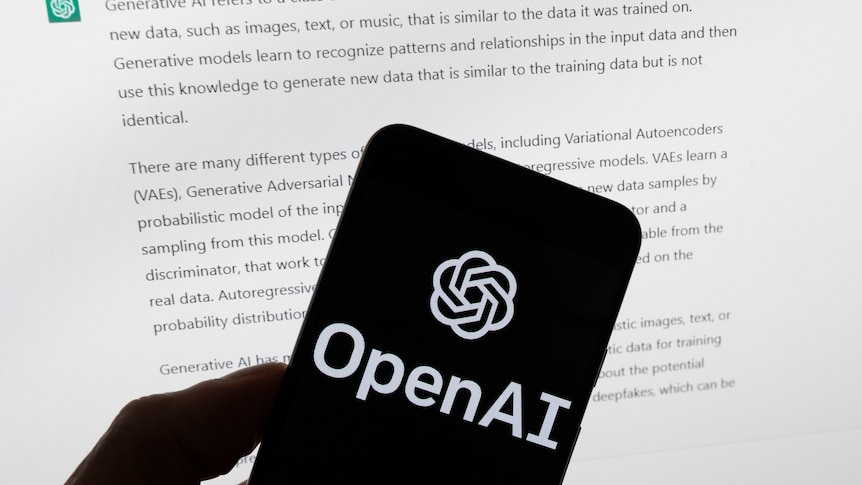 Logo Open AI is in white on black phone screen in front of a white computer screen with words. 