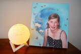 A photo of Chloe Myors at her father's home next to a light.