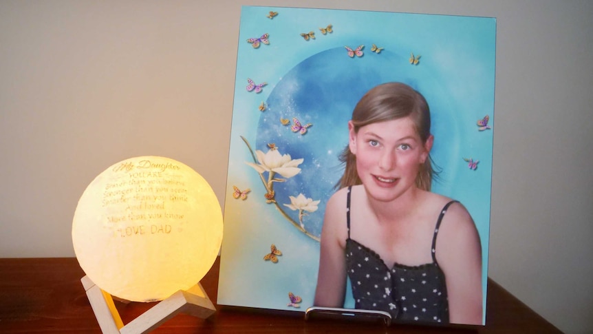 A photo of Chloe Myors at her father's home next to a light.