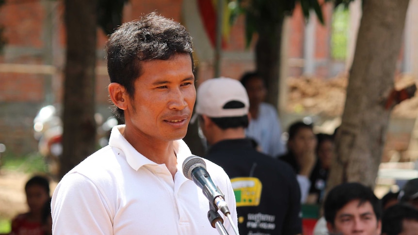 Young Cambodian man speaking at a public event into a microphone