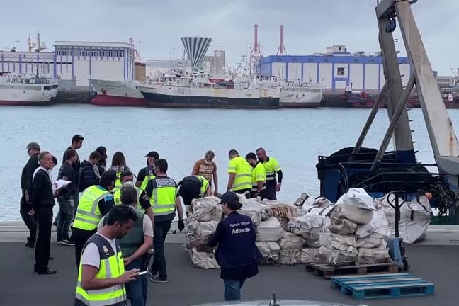 Police stand around a pile of bags on a dock