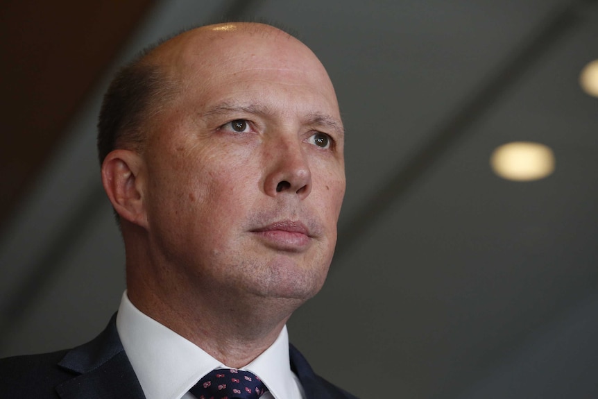 Peter Dutton looks forward with a serious facial expression.