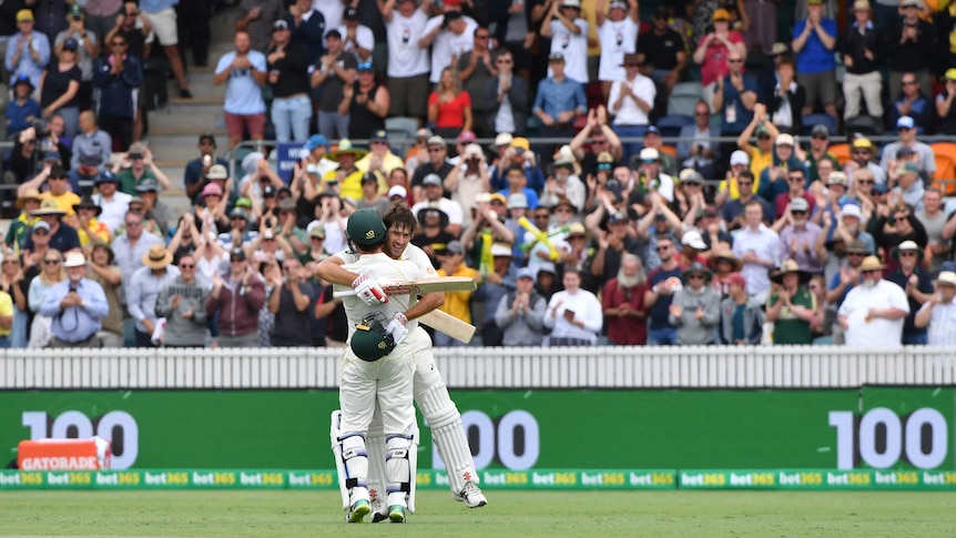 Joe Burns embraces Travis Head on the pitch as the Canberra crowd celebrates his century