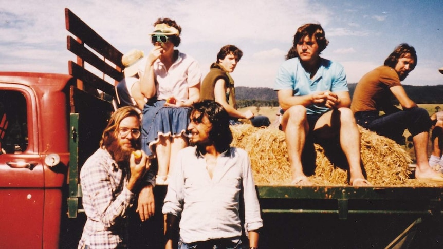 Fred Koch and other alternative community members on the back of a vintage red truck