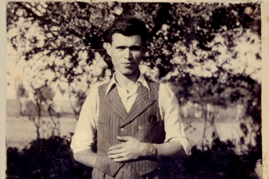 A black and white photo of Rai's father Romulus standing in front of a tree outside dressed in pants, waistcoat and white shirt.