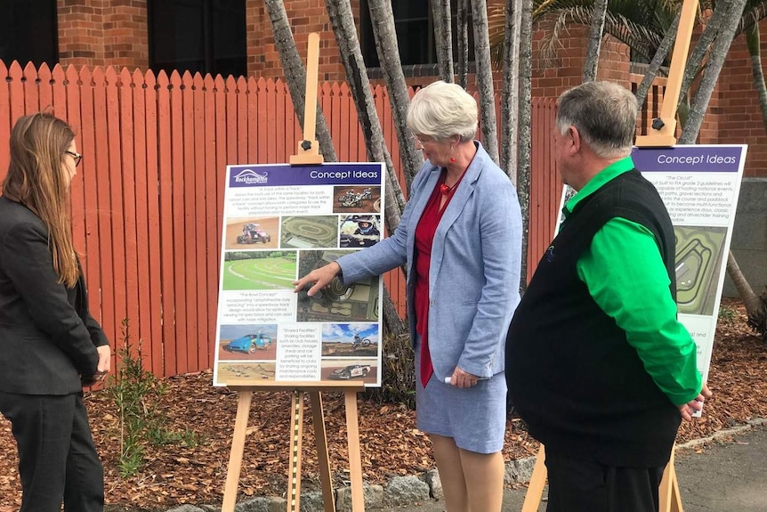 Three people look at a concept design ideas page in front of a fence