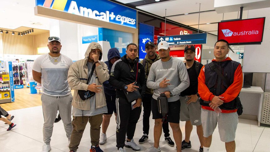A group of men in sportswear stand at Sydney international airport
