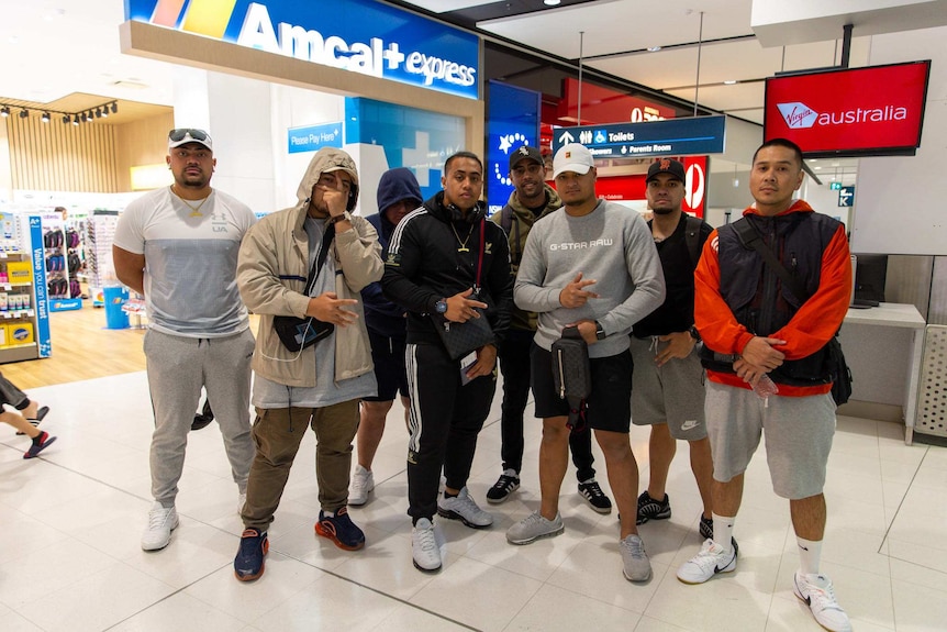 A group of men in sportswear stand at Sydney international airport