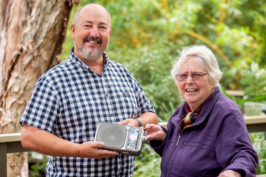 A man and woman stand together holding a radio.