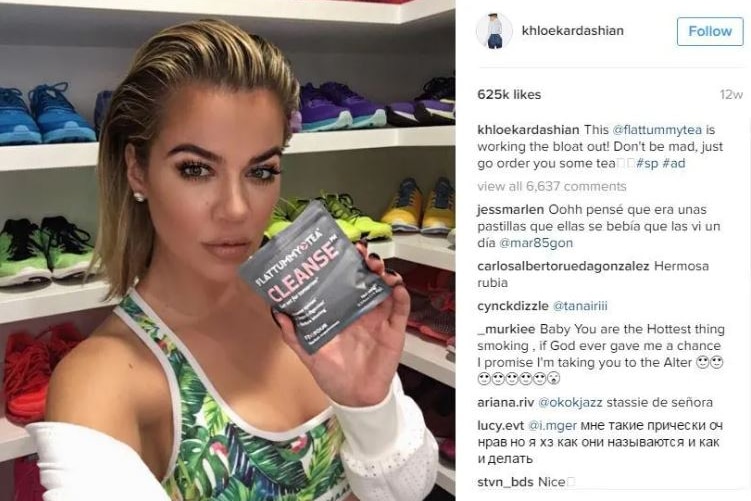 Selfie of Khloe Kardashian holding a grey sachet with 'flat tummy tea' written on it, with Instagram comments to the right.
