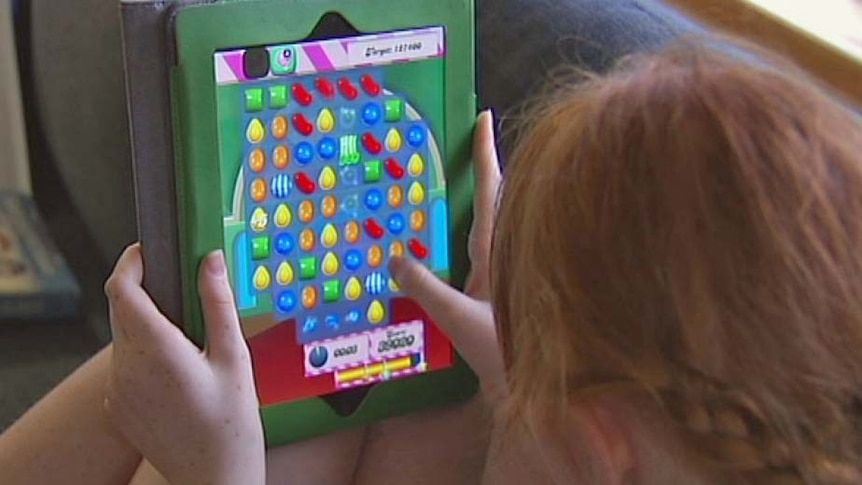 A teenager sits on a couch and plays with an app on an ipad.