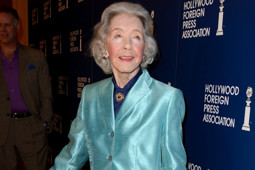 Marsha Hunt pictured in a satin blue jacket, with formal hair and make-up, at an event in her 90s.