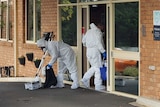Cleaners wearing full PPE hold cleaning equipment and walk into an aged care home.