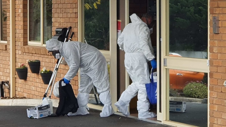 Cleaners wearing full PPE hold cleaning equipment and walk into an aged care home.