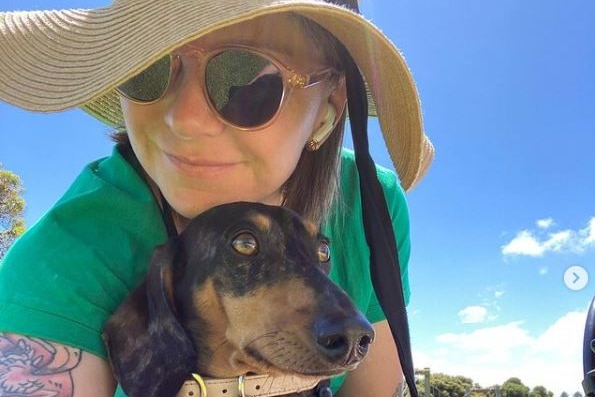 A close-up selfie shot of a woman outdoors with a dog.