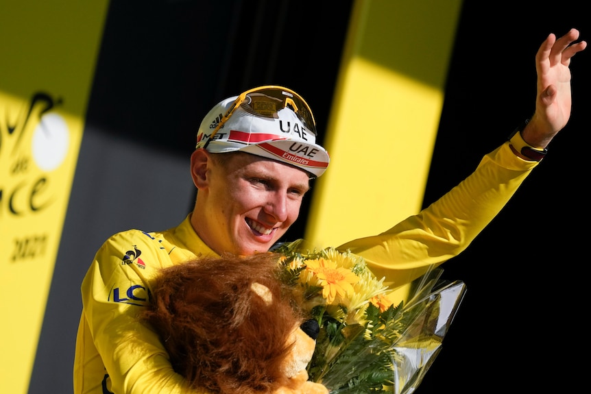 Slovenia's Tadej Pogacar, wearing the overall leader's yellow jersey, celebrates on the podium