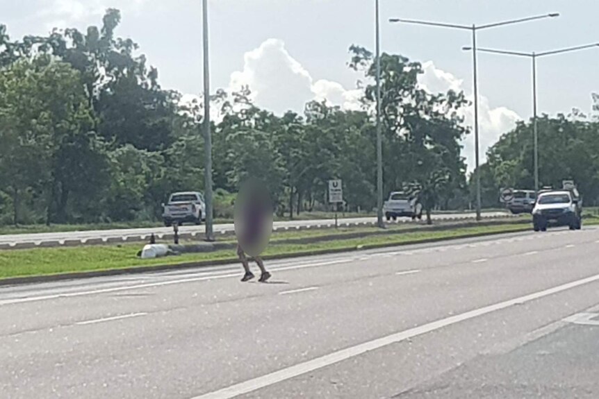 A photo of a student crossing a highway, with their figure blurred out.