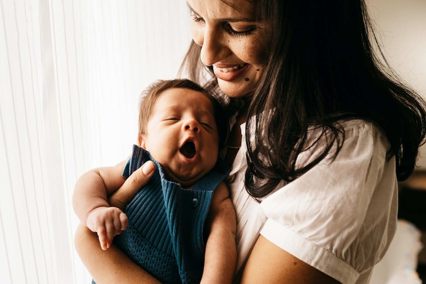Brunette woman indoors with her young baby
