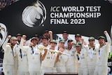 The Australian men's cricket team celebrate on a stage, as the captain holds the trophy after a tournament win.