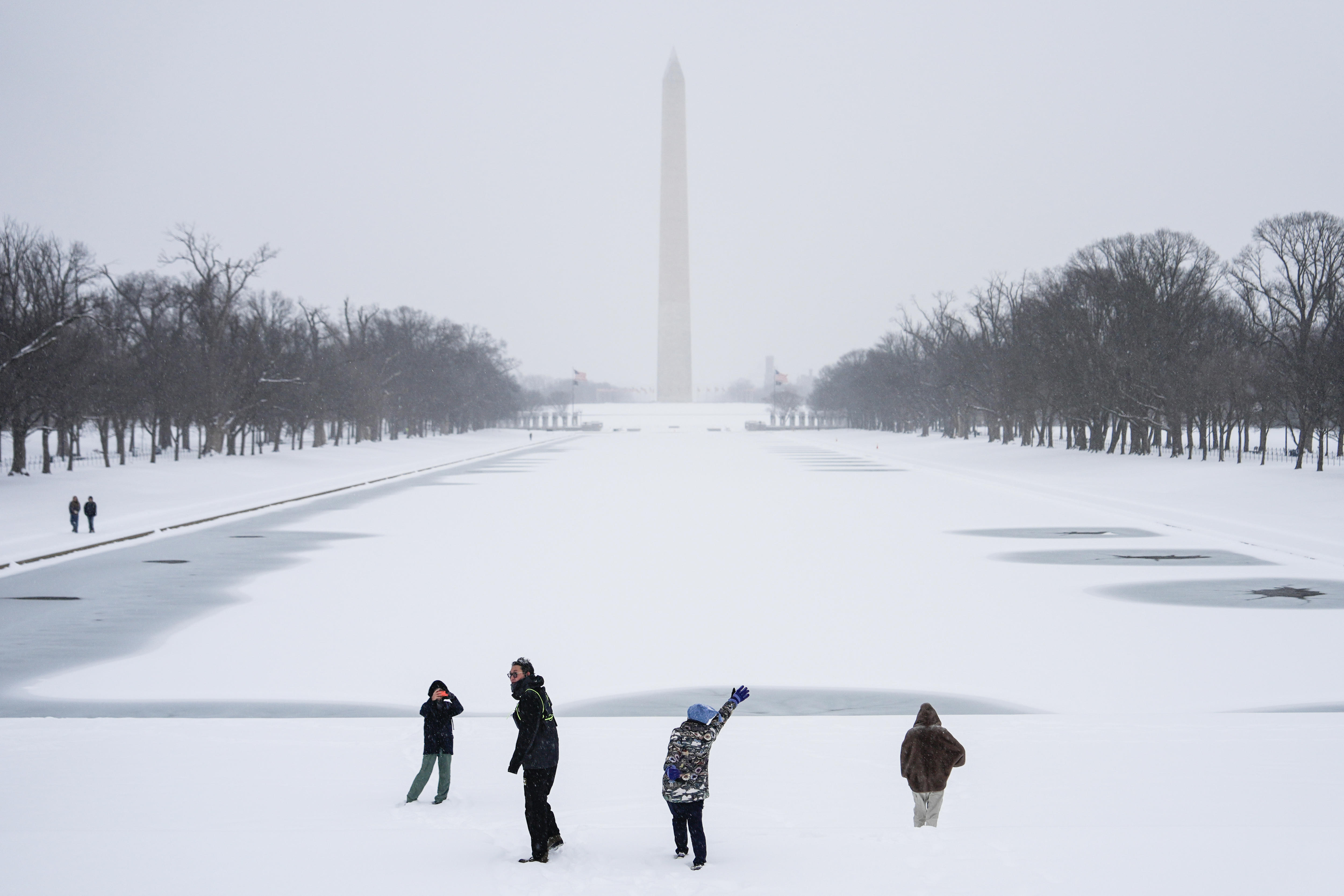 La gente juega en la nieve con el Monumento a Washington al fondo y una piscina congelada en memoria del Monumento a Lincoln. 