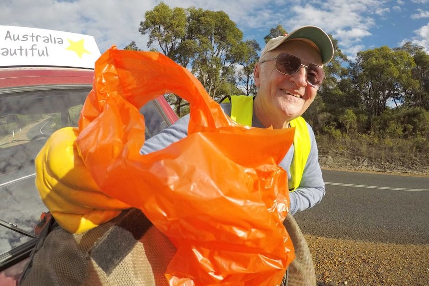 A man named Michael Filby smiling with a rubbish bag in hand collecting litter.