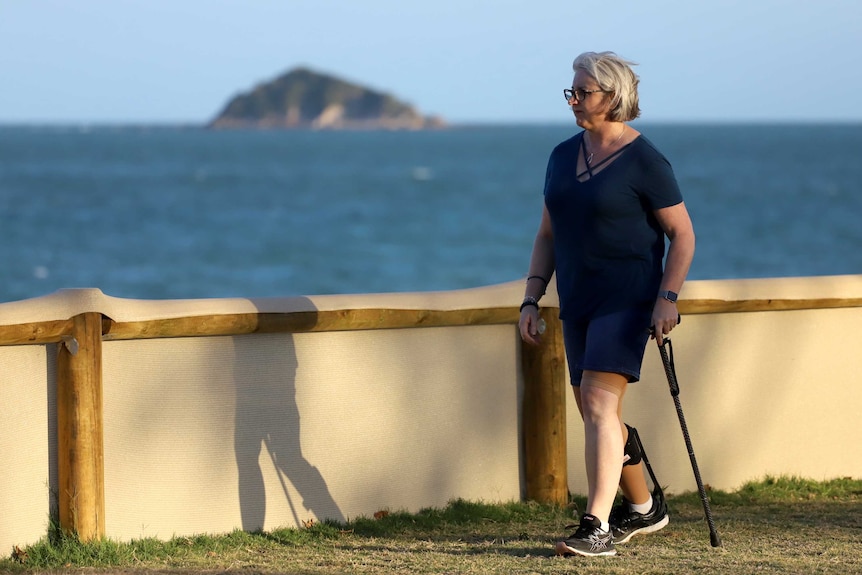 Woman with a walking stick near a beach.