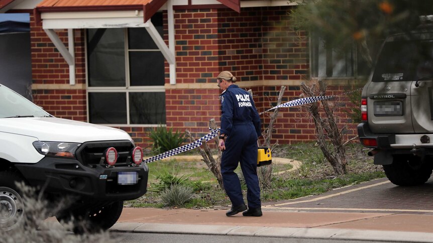 A female police forensic officer walks outside a brick house in the Perth suburb of Ellenbrook between two cars.