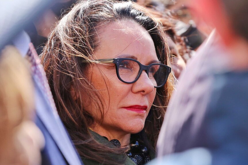 Tight close-up of a woman wearing glasses, not smiling.