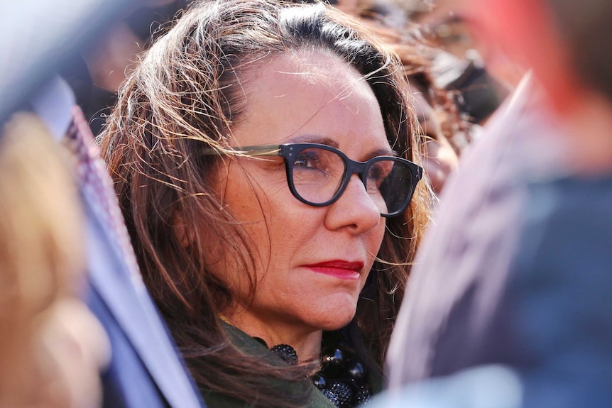 Tight close-up of a woman wearing glasses, not smiling.