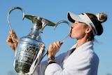 Nelly Korda kisses a large trophy after winning a golf tournament