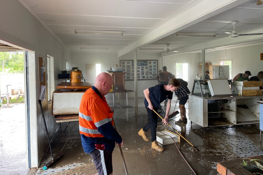 A number of people cleaning up the mud out of the brother club house