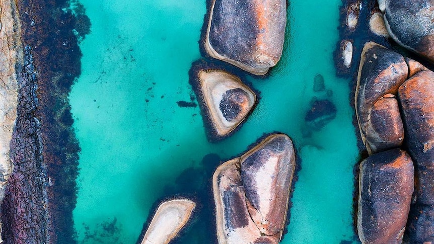 A drone photo of rocks gutting out of the ocean.