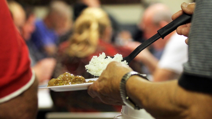 Close up on hands ladling food from pot to plate.