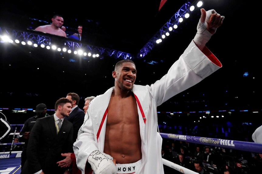 Boxer Anthony Joshua raises a fist in the ring after winning heavyweight fight